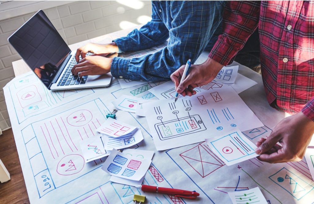 Lidí připravují plán pro UX design, píší na papíry a na notebooku